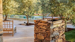 A stone barbecue grill with a metal frame, a wooden bench, and a tree in the background. - Olive Tree House - Two Bedroom Villa, Sleeps 4 (Fontelo)