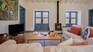 A cozy living room with a fireplace, comfortable seating, and a television. - Olive Tree House - Two Bedroom Villa, Sleeps 4 (Fontelo)