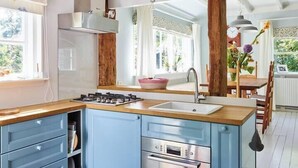 A modern kitchen with blue cabinets, a stainless steel Bosch oven, and a wooden countertop. - Cottage Duinroos - Dune Rose (Oostvoorne)