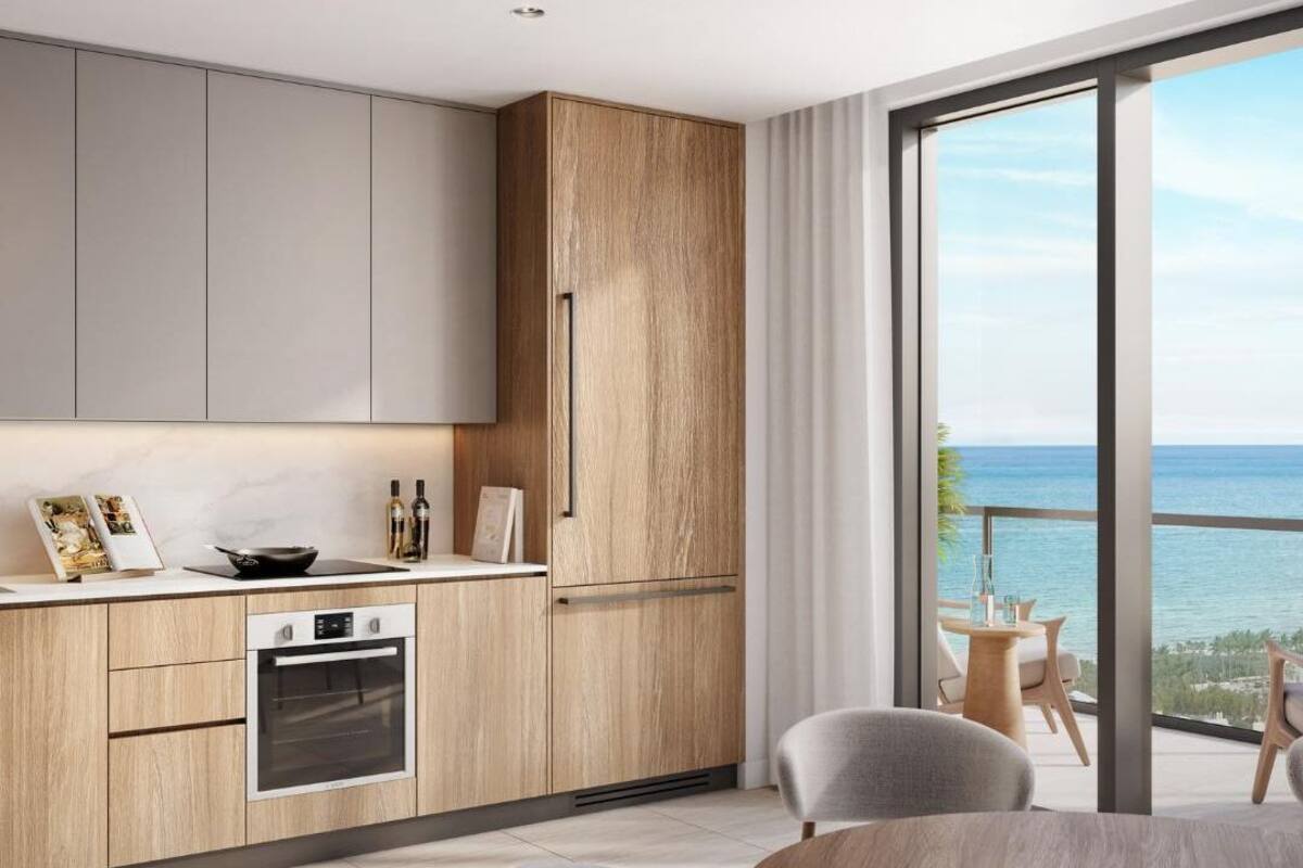 A modern kitchen with wooden cabinets and a large window overlooking the sea.
