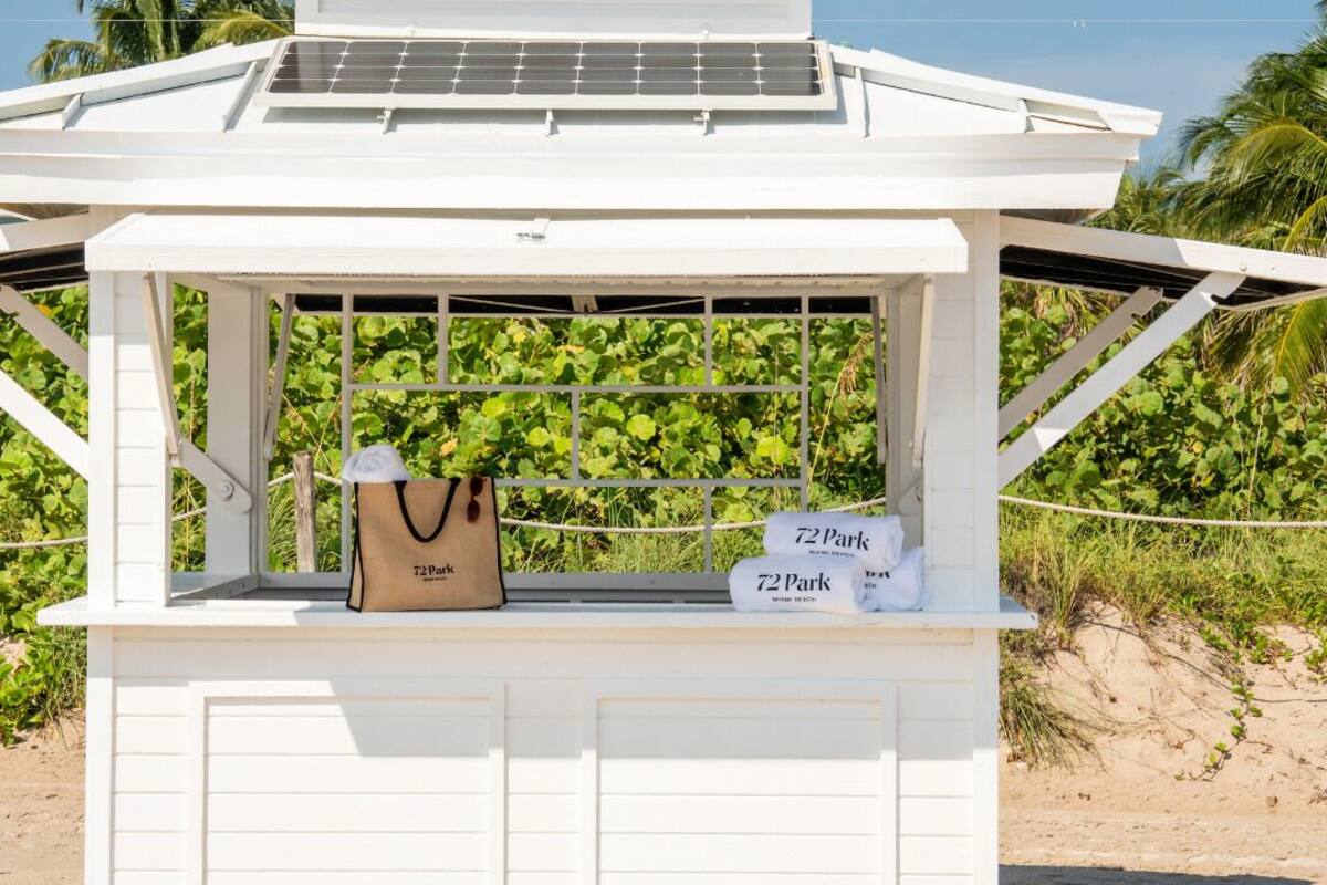 A beachside kiosk with a white roof, solar panels, and a sign reading "72 Park Miami Beach."