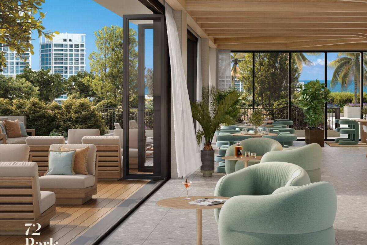 A modern outdoor lounge area with comfortable seating, a view of the ocean, and a clear sky.