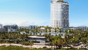 A high-rise hotel with a curved facade, a rooftop garden, and a beachfront location with palm trees and beach umbrellas. - 580 Residance (Miami Beach)