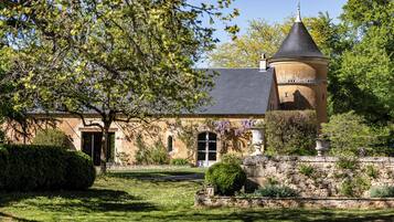 A historic building with a tower, a well-maintained lawn, and a stone wall.