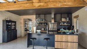 A modern kitchen with a central island, bar stools, and wooden beams on the ceiling.