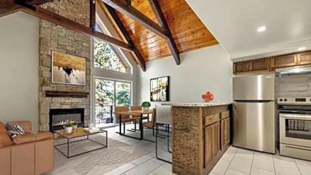 Una cocina moderna con chimenea de piedra, vigas de madera y electrodomésticos de acero inoxidable.