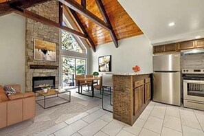 Eine moderne Küche mit Kamin aus Naturstein, Holzbalken und Edelstahlgeräten.