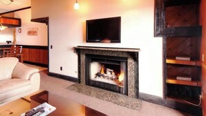 A living room with a fireplace, a television mounted on the wall, and a sofa.