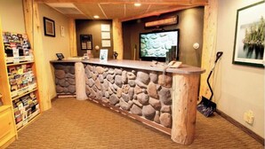 A reception area with a stone wall, wooden counter, and a television screen.