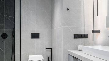 A modern bathroom with a glass shower enclosure, a toilet, and a vanity with a mirror.