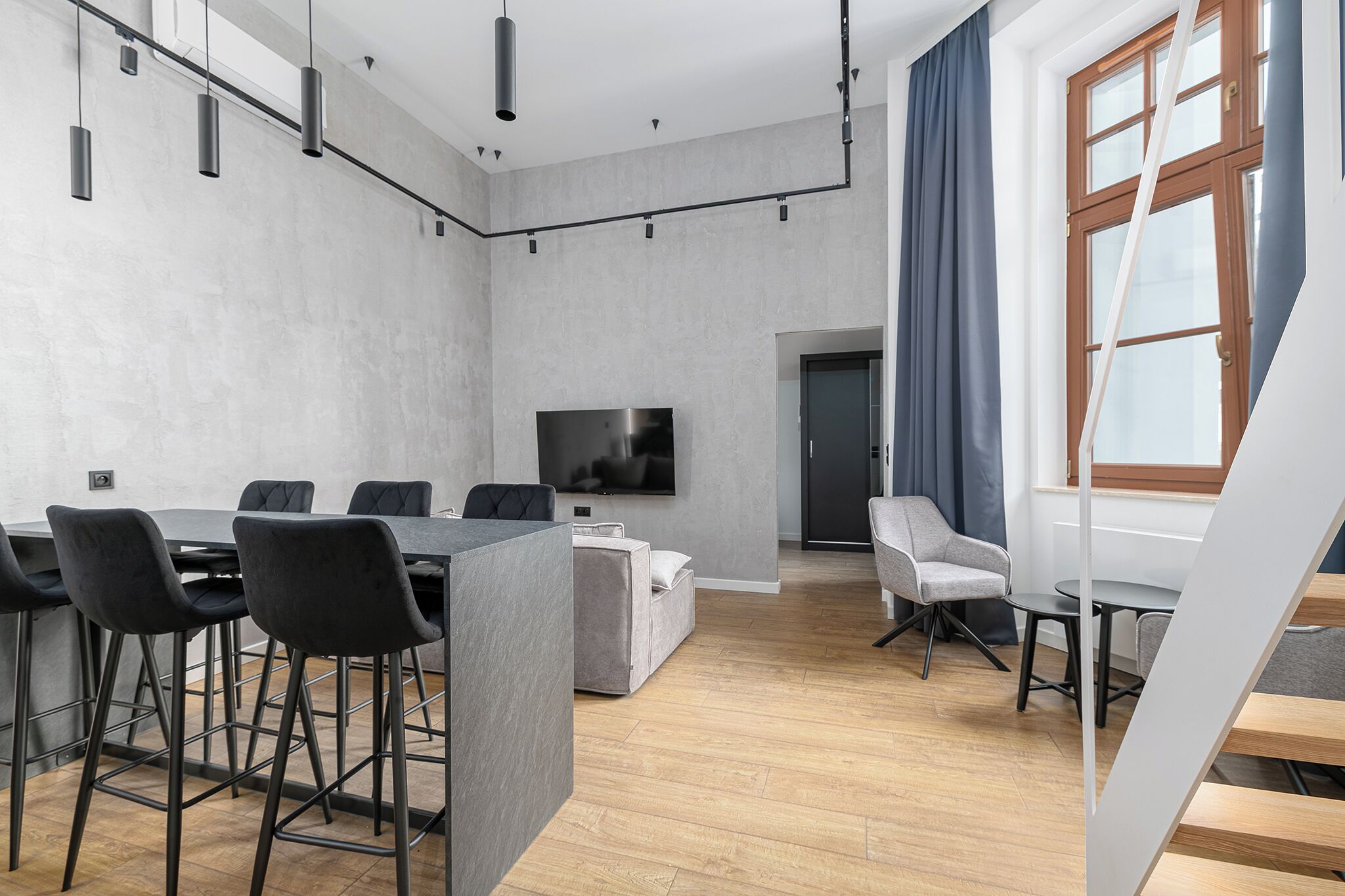 Una sala de reuniones moderna con una mesa larga, sillas, una televisión y una escalera.