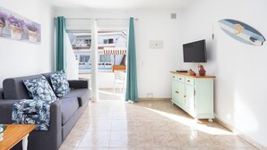Un salon comprenant un canapé, un téléviseur, un meuble et une décoration sur le thème du surf.