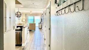 A hallway with a view to a balcony, a dining area, and a kitchen.