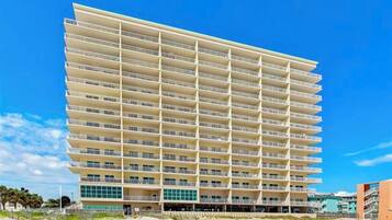 A multi-story hotel with a uniform facade, balconies on each floor, and a flat roof.