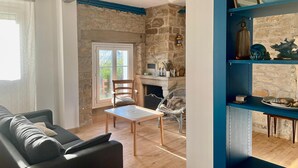 A living room with a stone fireplace, a wooden coffee table, and a blue shelving unit. - L'Authentik (Gouesnach)