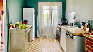 A compact kitchen with a checkered floor, a refrigerator, a sink, and a stove. - L'Authentik (Gouesnach)