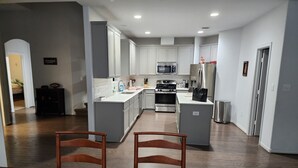 A modern kitchen with white cabinets, stainless steel appliances, and a central island.