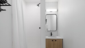 A modern bathroom with a shower, a sink, and a mirror. - HI Halifax Heritage House - Hostel (Halifax)