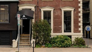 A two-story brick building with a green roof and white trim. There is a black awning with the text "HI HALIFAX" and a no parking sign. - HI Halifax Heritage House - Hostel (Halifax)