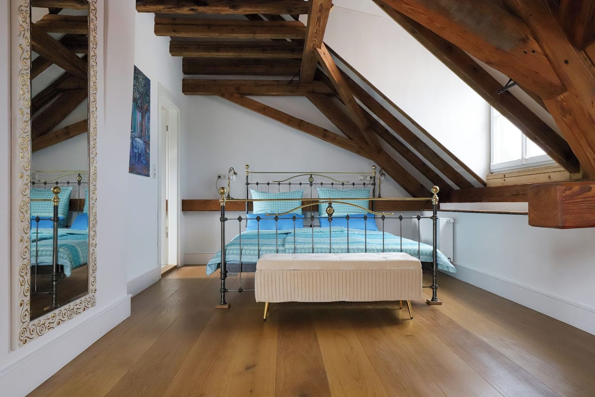 A bedroom with a wooden ceiling, a metal bed frame, and a large mirror.
