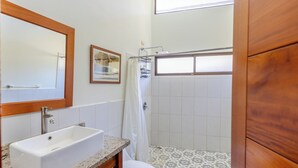 Un baño con lavamanos blanco, inodoro y zona de ducha.