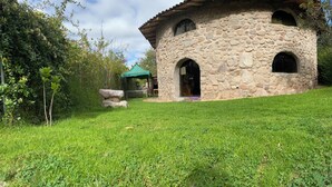 A stone building with a covered entrance, surrounded by greenery. - ILLA WASI SACRED VALLEY - BUNGALLOW 3 ROOMS (Urubamba)
