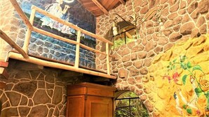 A stone-walled room with a wooden ceiling, a window with a wooden frame, and a chandelier. - ILLA WASI SACRED VALLEY - BUNGALLOW 3 ROOMS (Urubamba)