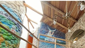 A rustic interior with stone walls, a wooden ceiling, a staircase, a wooden cabinet, and a television mounted on the wall. - ILLA WASI SACRED VALLEY - BUNGALLOW 3 ROOMS (Urubamba)