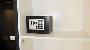 A room with a white wardrobe, a black-framed mirror, and a white shelf with a black object.