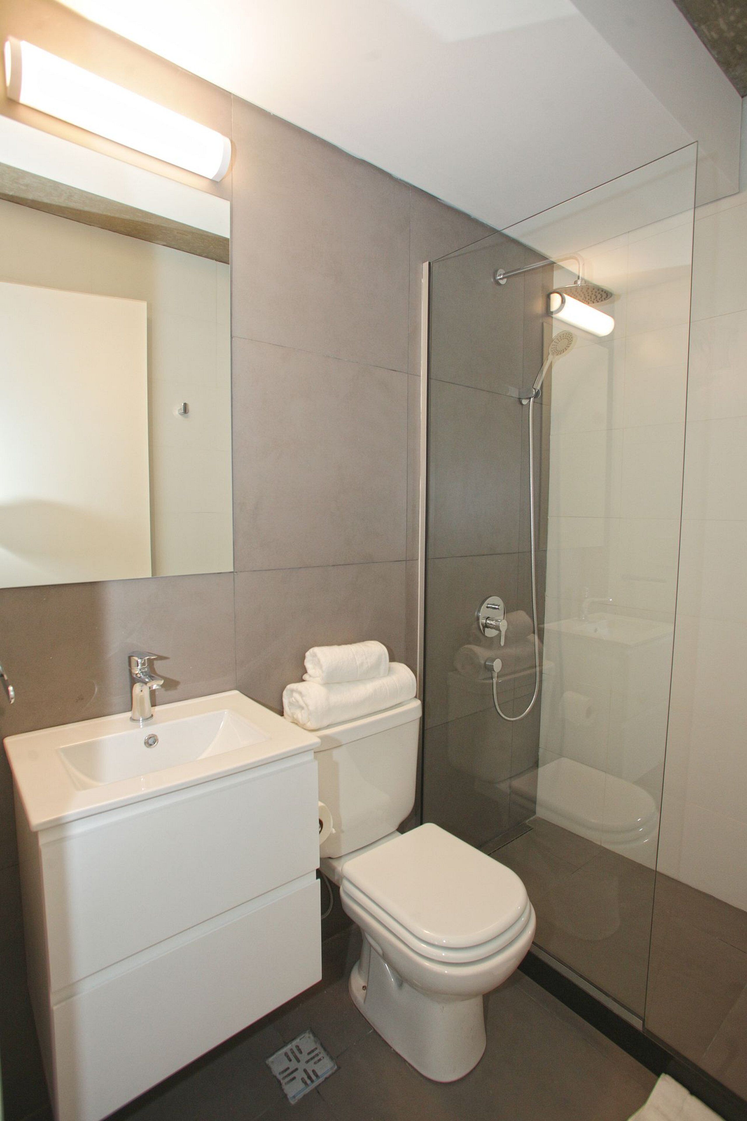 Une salle de bain moderne avec une douche à parois de verre, un lavabo blanc et des toilettes.