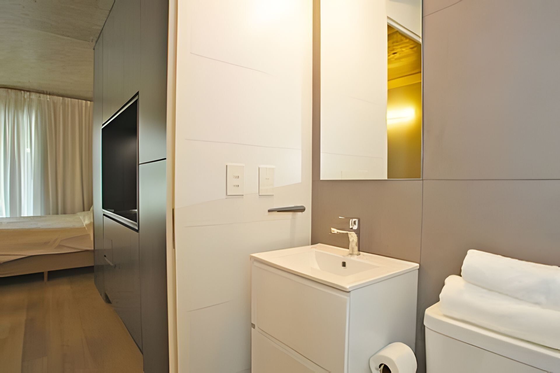 Un baño moderno con lavamanos, inodoro y espejo.