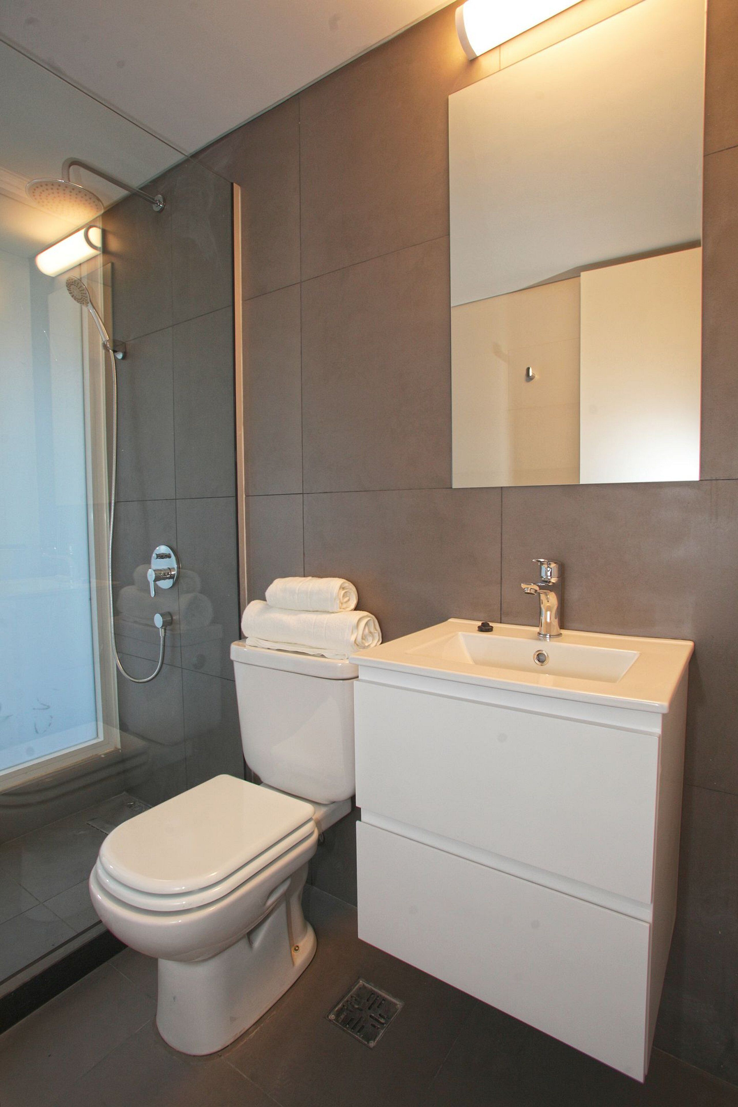 A modern bathroom with a toilet, sink, and shower.