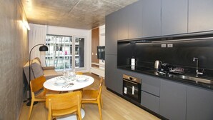 Une cuisine moderne avec des meubles gris, un plan de travail noir et un four encastré.