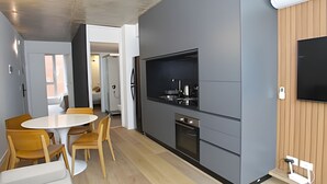 Een moderne keuken met grijze kastjes, een inbouwoven en een flatscreen televisie aan de muur.