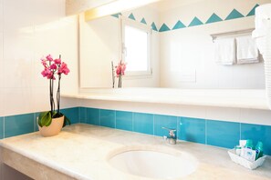A bathroom with a sink, a mirror, a potted orchid, and a towel rack. - Baia Orosei Apartments Ac (Orosei)