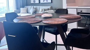A modern dining area with a round table, black chairs, and woven placemats.