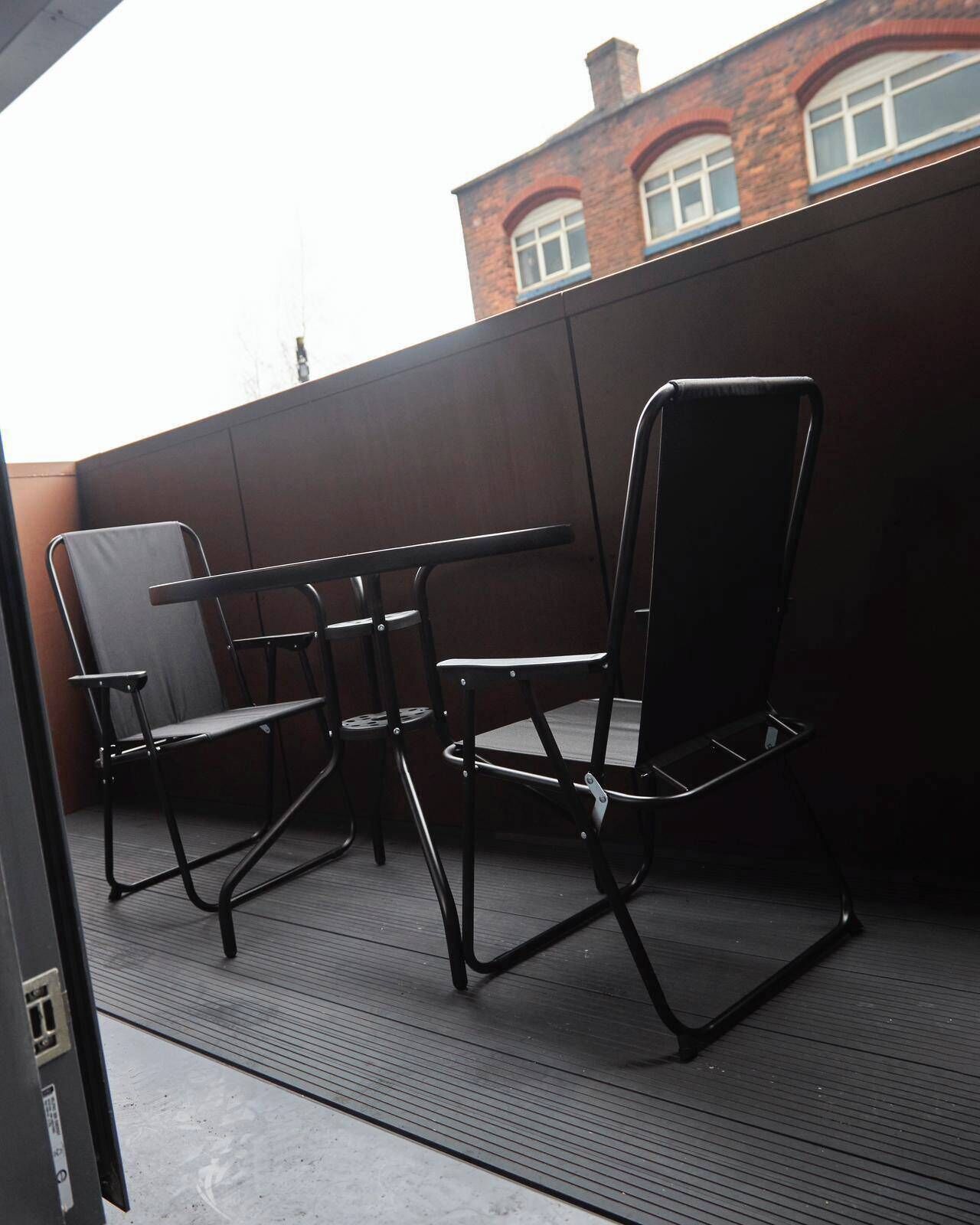 Eine Terrasse mit Tisch und vier Stühlen.