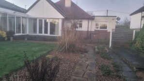 A residential property with a stone pathway leading to a white house with a brick extension. - Charming Home in Huddersfield w/ Parking Petsok (Huddersfield)