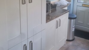 A kitchen with white cabinets, a microwave, and a trash bin. - Charming Home in Huddersfield w/ Parking Petsok (Huddersfield)