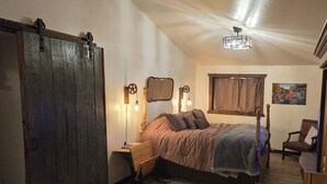 Un dormitorio con cama, escritorio, silla, armario y un cuadro en la pared.