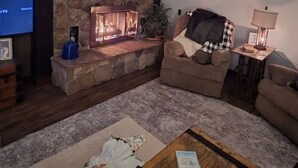 Una sala de estar acogedora con chimenea de piedra, un televisor y una cabeza de venado montada.