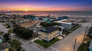 A coastal town with a prominent building featuring a balcony and a view of the ocean. - The Lookout at R½ | Hot Tub • Sauna • Wraparound Deck • Steps to Beach (Galveston)