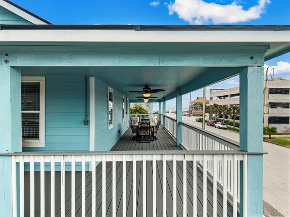 A covered porch with a railing, a ceiling fan, and a view of the street.