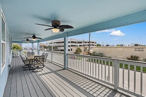 Ein überdachter Außenbereich mit Tisch und Stühlen, Deckenventilatoren und Blick auf eine Parkgarage.