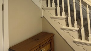 A staircase with white balusters and a wooden bench at the bottom.