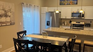 A modern kitchen with white cabinets, stainless steel appliances, and a dining area with a table and chairs.
