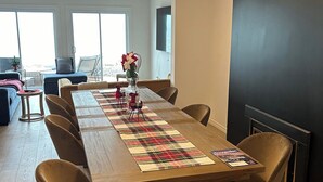 A dining area with a long wooden table, six chairs, and a plaid runner.