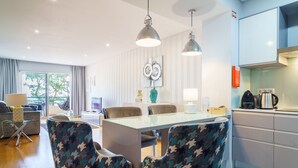 Un espace de salle à manger moderne avec une table en verre, des chaises à motifs et des luminaires suspendus.