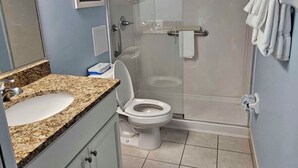 Ein Badezimmer mit Granitwaschtisch, Toilette in Weiß und einer Duschkabine aus Glas.