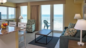 Ein Hotelzimmer mit Balkon, einem Essbereich mit Tisch und Stühlen, einer Couch und einem Fernseher.